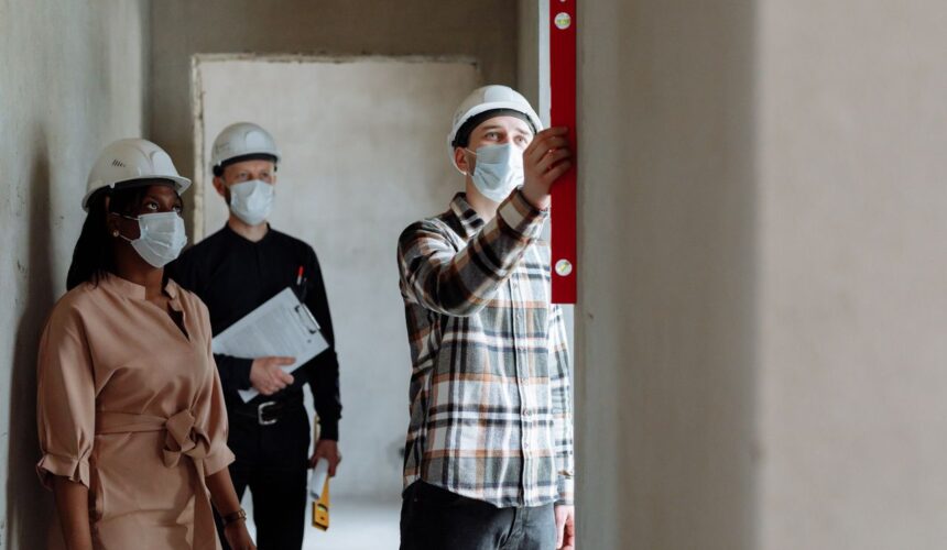 Team of construction workers in hard hats and masks inspecting indoors