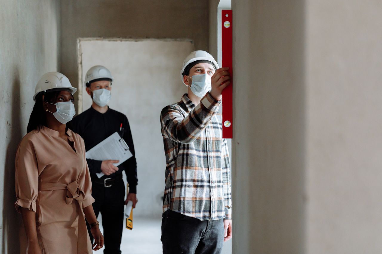 Team of construction workers in hard hats and masks inspecting indoors
