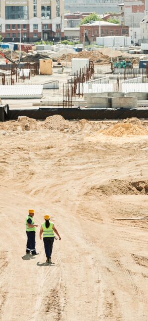 Overhead drone shot of a construction site with two workers in safety gear.