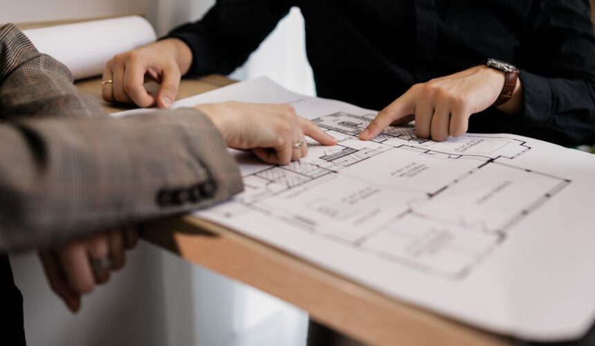 Two architects reviewing and pointing at a detailed floor plan on paper