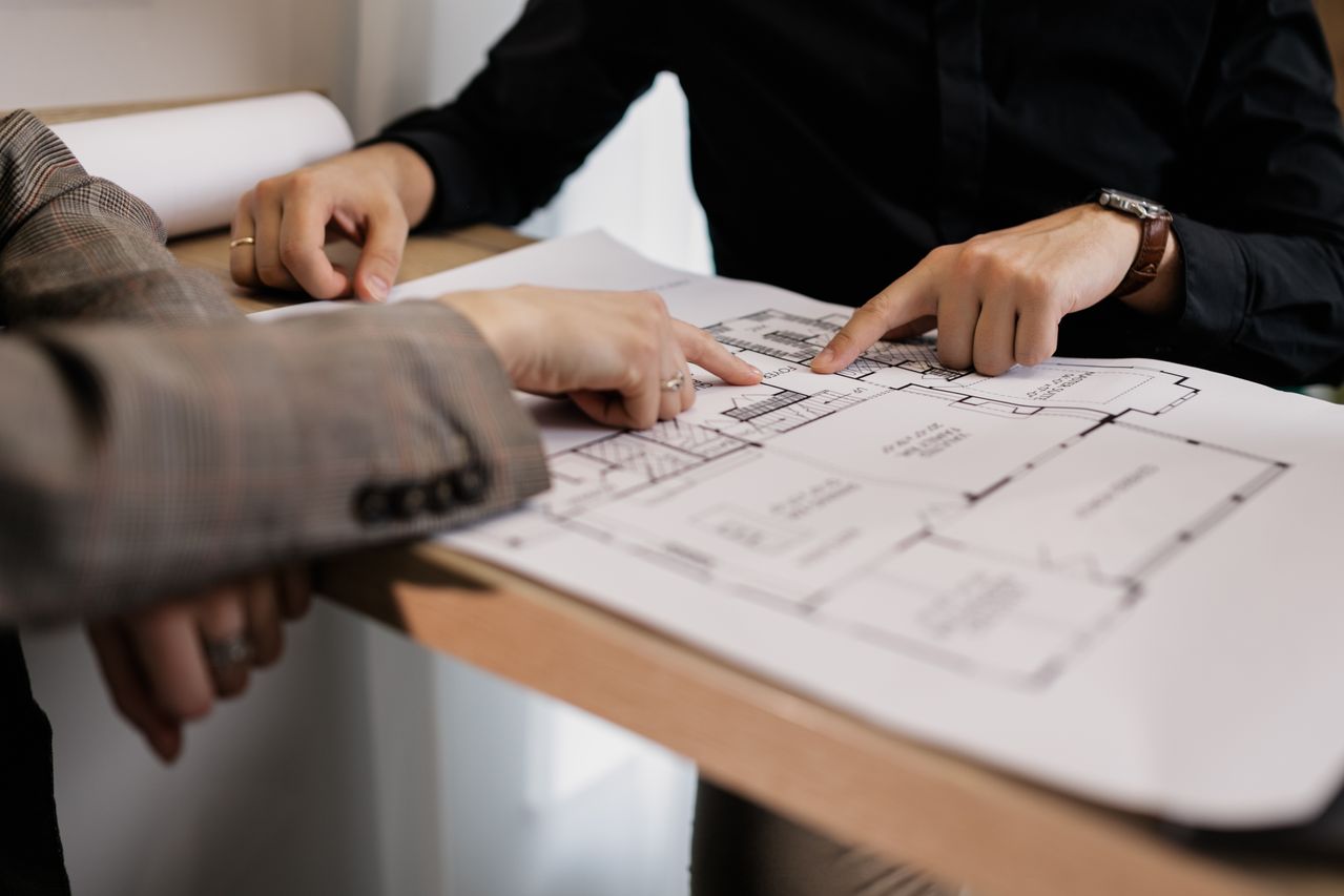 Two architects reviewing and pointing at a detailed floor plan on paper