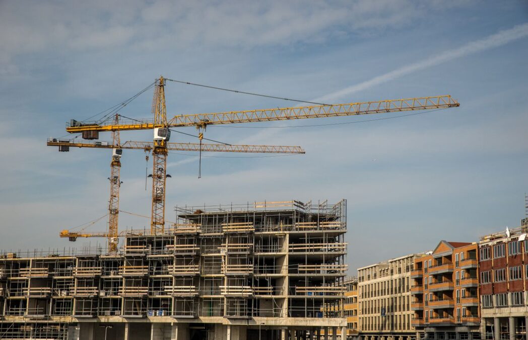 construction site with cranes and partially built structures under a clear sky.