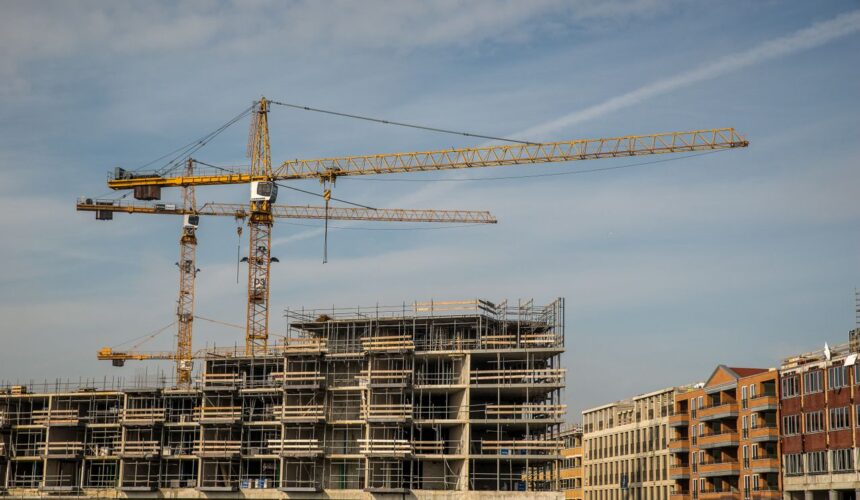 construction site with cranes and partially built structures under a clear sky.