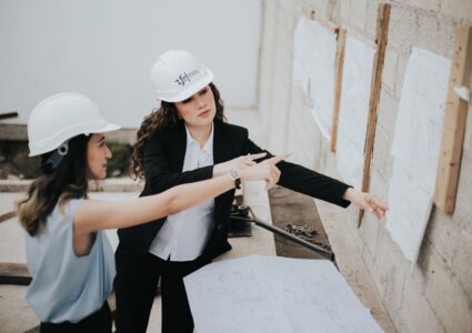 Two female architects discussing building plans outdoors