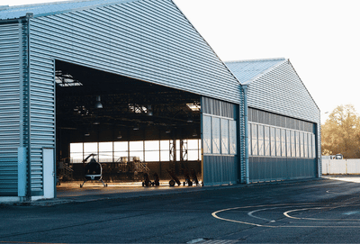 A modern industrial hangar exterior with a helicopter visible, offering spacious interior views.